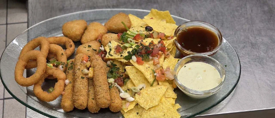 Knusperplatte mit Nachos, Zwiebelringen und Dips